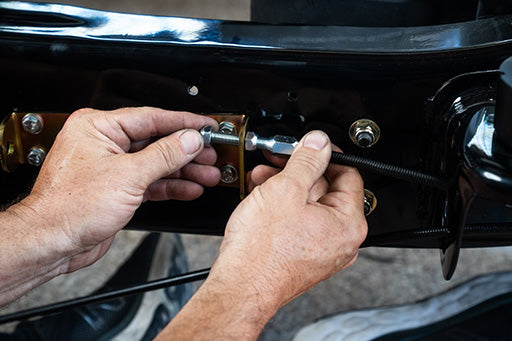 A person's hands connecting parking brake cables to the E-Stopp brake cable junction bracket