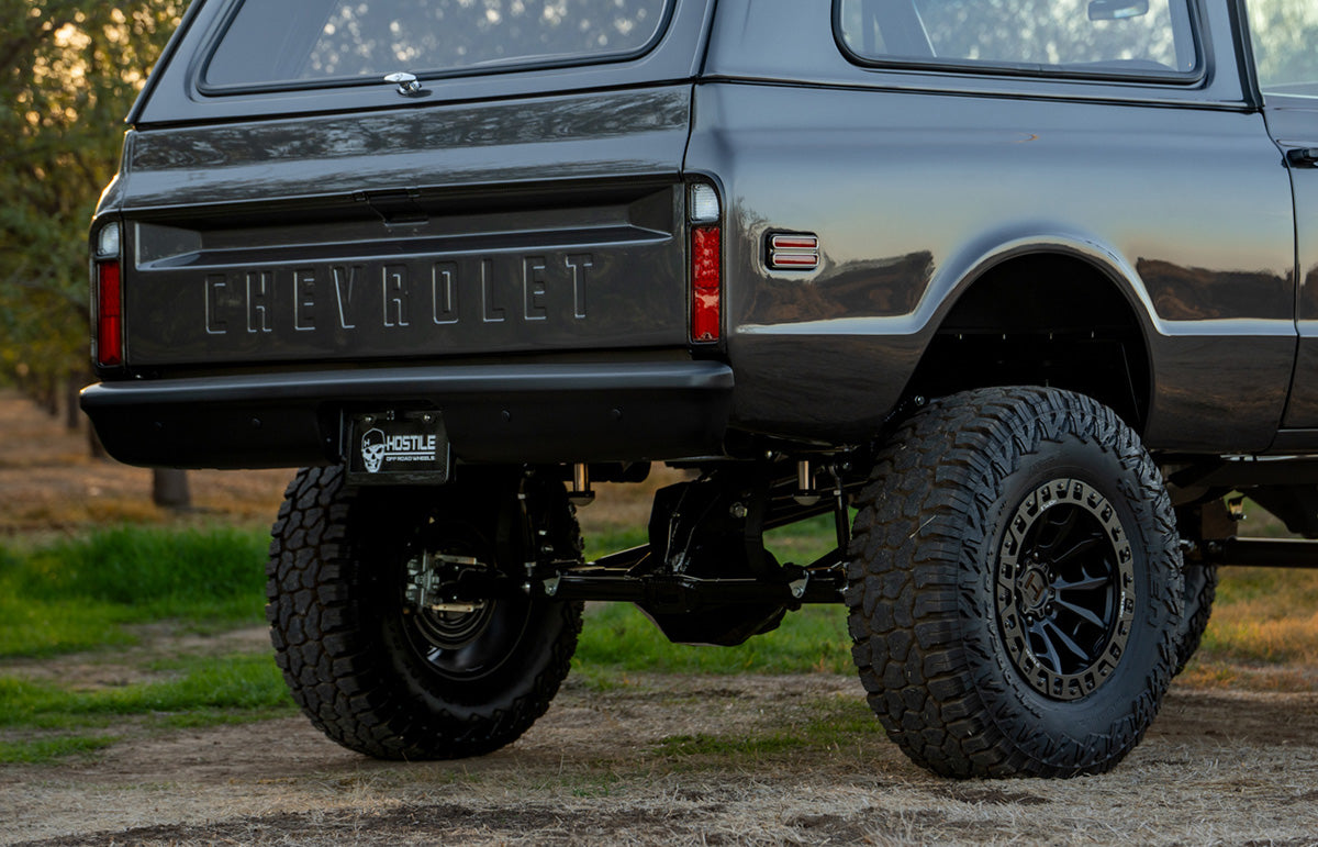 Rear axle of PPC Blazer parked in a field with trees in the background