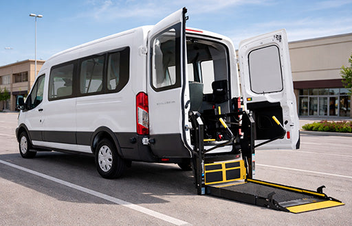 Ford Transit van with a wheelchair ramp extended in a parking lot.
